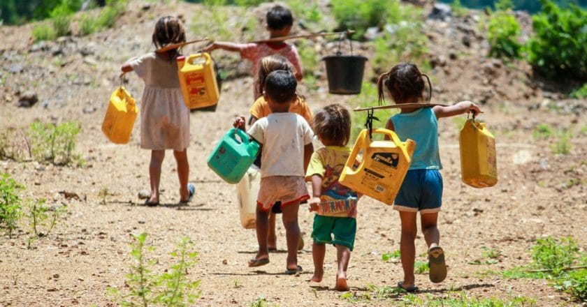 A group of children walking to a nearby river to get water.