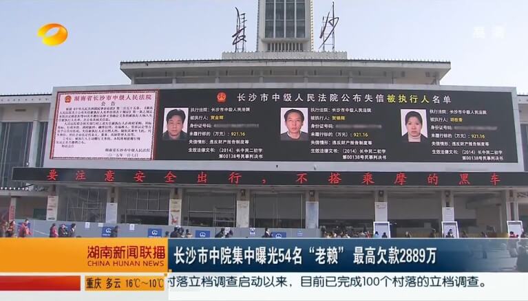 Ekran wstydu w mieście Changsha, na którym wyświetlane są zdjęcia i dane chińskich dłużników. Fot. screenshot CNN