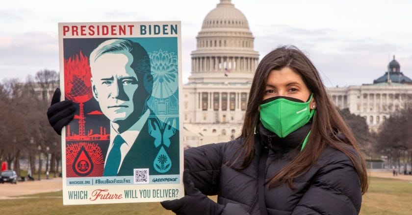 Greenpeace USA activist Jenna DiPaola holds a poster with a new art collaboration by graphic artist Shepard Fairey and Greenpeace USA pushing President Joe Biden to end the era of fossil fuel racism and deliver on the promise of a Green New Deal.  The U.S. Capitol is visible in the background.
The new piece Fairey designed for Greenpeace and the climate movement depicts two possible futures: one in which Joe Biden delivers on his promises to prioritize climate and environmental justice, and one in which fossil fuel corporations escape accountability for their decades of pollution and deceit.