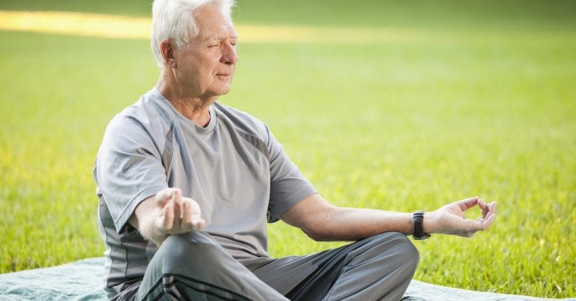 Senior man (60s) meditating, in lotus pose.